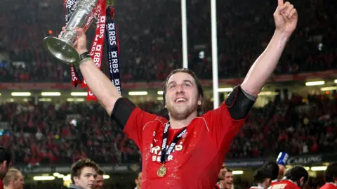 PA Media Former player Ryan Jones celebrating with a red Wales shirt and a medal around his neck