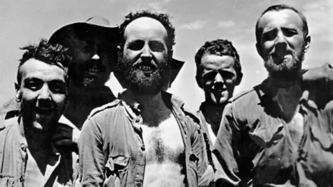 Getty Images A black and white photo of soldiers during World War Two in Burma. They wear thin shirts with some buttons undone exposing their chests.