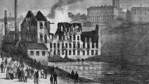 Hulton Archive/Getty Images A black and white drawing showing a burned out mill by a river in Haslingden. There are two more mills on a hill to the top right and people walking by on a path in the bottom left