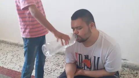 Family handout Muhammed Bhar is given water from a bottle