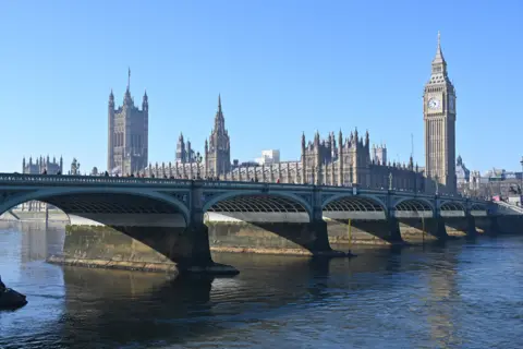 Westminster Bridge is pictured with a blue sky and the Houses of Parliament in the background