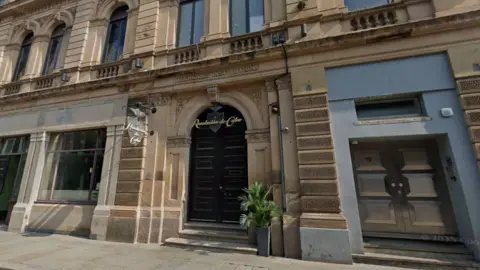The exterior of Revolucion de Cuba, which has a large arched door and has a cream stone exterior