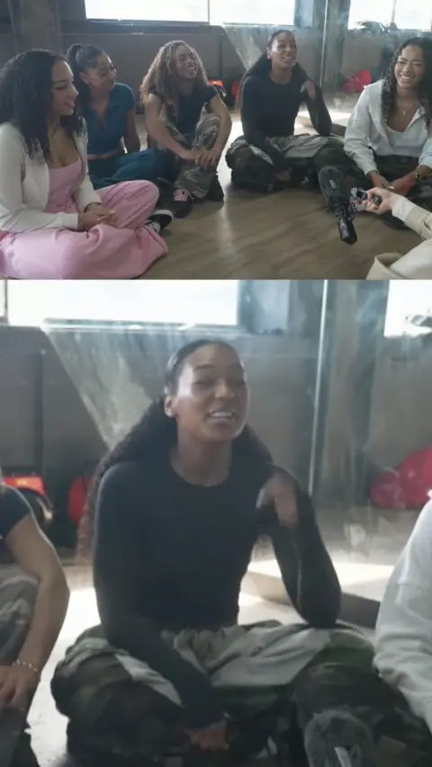 A split screen image of 5 girls sat down, and the bottom image is zoomed in on one smiling girl