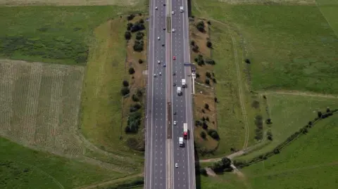 An aerial view of the M5 motorway near Tewkesbury in Gloucestershire, with green fields either side.