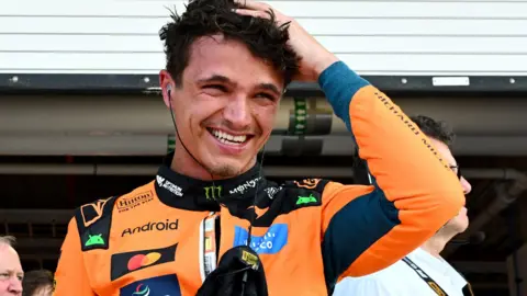Lando Norris smiles as he runs his hand through his hair after taking pole position for the Miami Grand Prix sprint race