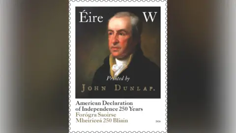 An Post A stamp features a portrait of a man wearing a white top tied at the throat and a back coat. The stamp says: Eire W printed by John Dunlap. American Declaration of Independence 250 years. Forógra Saoirse Mheiriceá Bliain