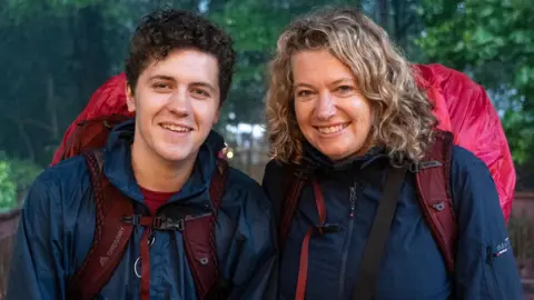Dylan Llewellyn and mum Jackie standing together with raincoats and backpacks during the race
