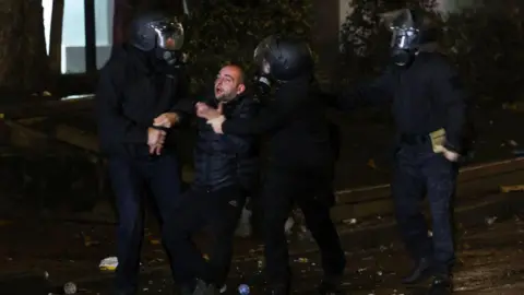 Getty Images A demonstrator is detained by police during protests in Tbilisi