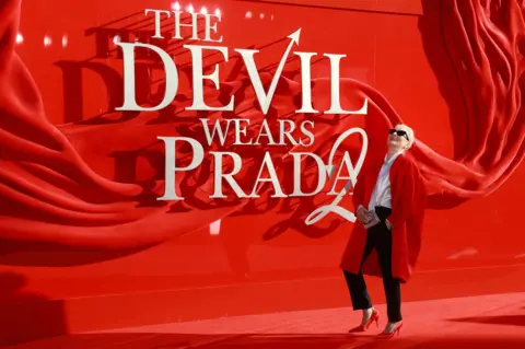 Getty Images Meryl Streep stands smiling on the red carpet next to a "The Devil Wears Prada 2" sign.