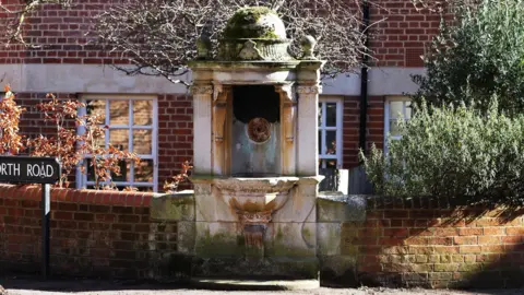 The stone fountain protrudes from a smaller red brick wall.