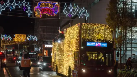 Brighton and Hove Buses A double decker bus covered in Christmas lights being driven through busy streets in Hove.
