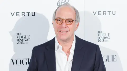 Loyd Grossman wearing a suit and glasses