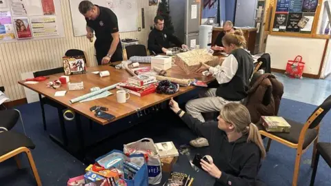 Surrey Fire and Rescue Service staff from the fire service wrapping Christmas gifts in an office