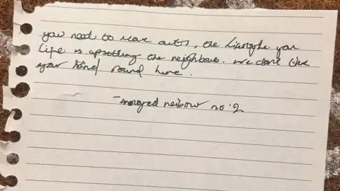 Alex Houlden A hand written message that reads: "You need to move out, the lifestyle you live is upsetting the neighbours. We don't like your kind round here."

It's signed off: "annoyed neighbour no 2".