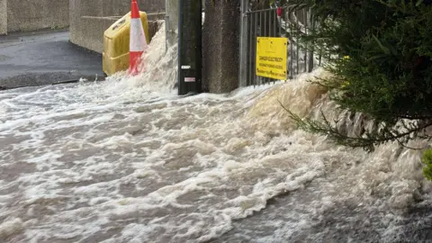 Samuel Geist Flood water is gushing downhill through an electricity station. 