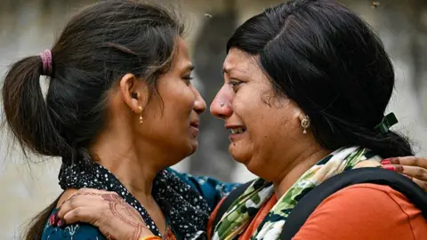 Women mourn as the bodies of their relatives, killed the previous day after Air India flight 171 crashed in a residential area, are taken out of a hospital mortuary in Ahmedabad on June 13, 2025. Rescue teams with sniffer dogs combed the crash site on June 13 of a London-bound passenger jet which ploughed into a residential area of India's Ahmedabad city, killing at least 265 people on board and on the ground. (Photo by Punit PARANJPE / AFP) (Photo by PUNIT PARANJPE/AFP via Getty Images)
