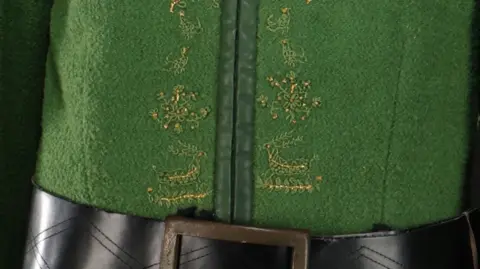 Propstore A close up of the green tunic showing gold stitching