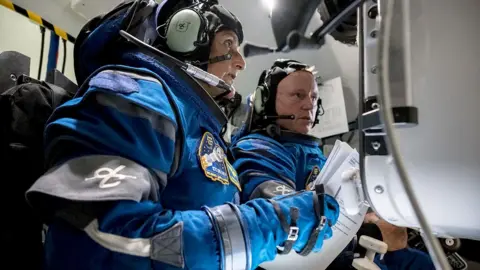 Getty Images NASA astronauts Suni Williams and Butch Wilmore wearing blue space suits while training in a space simulator at NASA's Johnson Space Center in November 2022.