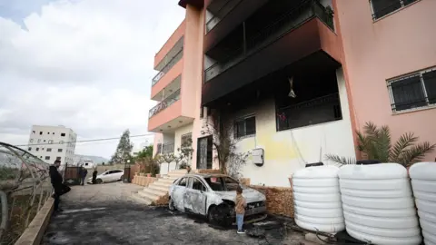 EPA Palestinians inspect the damage in the village of Deir al-Hatab, in the occupied West Bank, following an attack by Israeli settlers (23 March 2026)