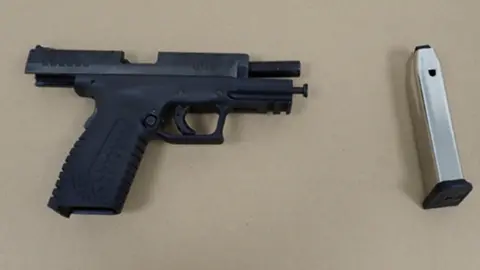 PA Media Police evidence image of black handgun and magazine against a brown background