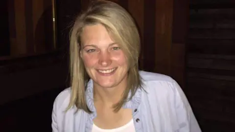 Family handout A woman with blonde hair smiling widely with a purple shirt.