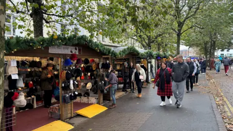 People walking through York Christmas Market on Parliament Street, with the Hat Shop in view 