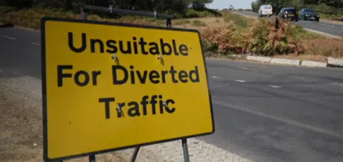 A yellow traffic warning sign for diverted vehicles 