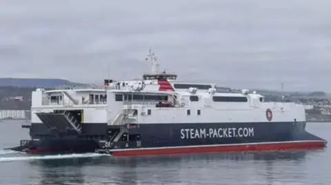 The fast craft Manannan ferry in Douglas Bay. It is painted in the white, black and red colours of the Isle of Man Steam Packet Company and has STEAM-PACKET.COM on the side in white lettering.