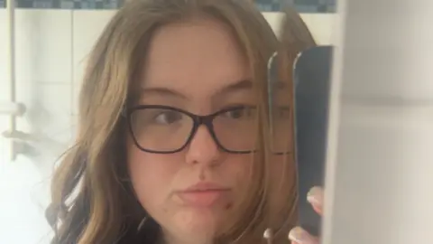 Felicity Etheridge Felicity is wearing glasses and has brown hair. She is taking selfie.