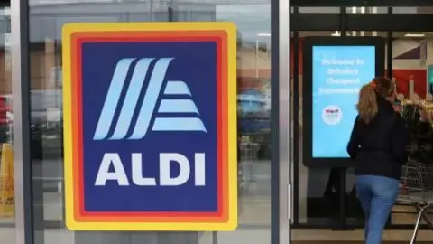 REUTERS/PHIL NOBLE Customer entering an Aldi store 