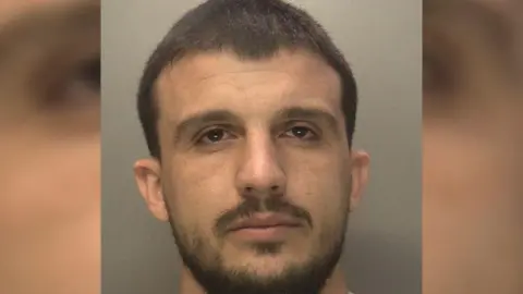 Donaldo Mateau seem with brown eyes, short black hair and a black beard. 