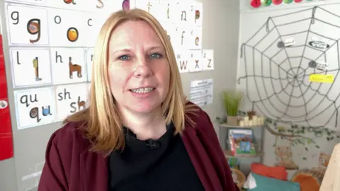 A woman stood in front of primary classroom displays