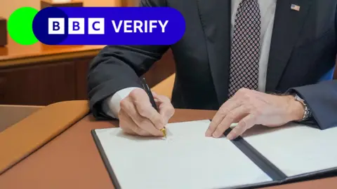 White House Close-up of President Joe Biden signing a pardon while on Air Force One. The BBC Verify logo appears in the top corner.