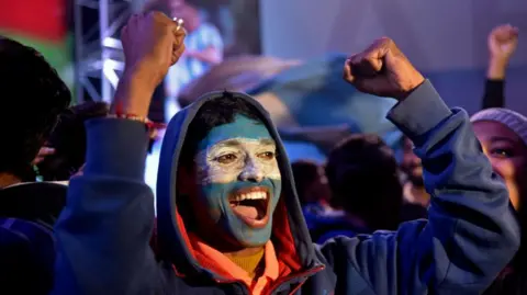 A fan of the Argentina football team raises his fists in the air while watching the Argentina v France final at a viewing party in Kolkata, India 