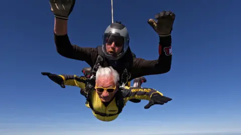 Skydive Buzz John Landau freefalling through the air, with a man strapped to his back