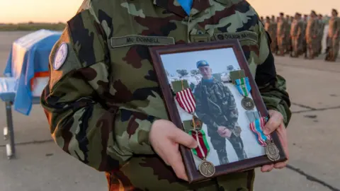 Irish Defence Forces Soldier holding framed picture of Private Sean Rooney