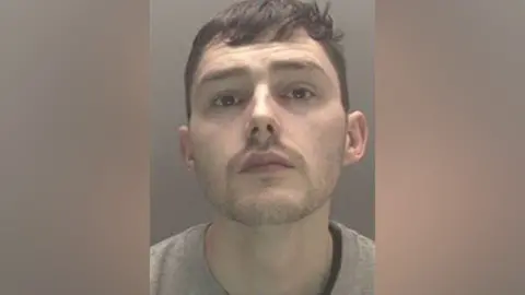 Thames Valley Police A mugshot shows a man with short brown hair and a stubble.