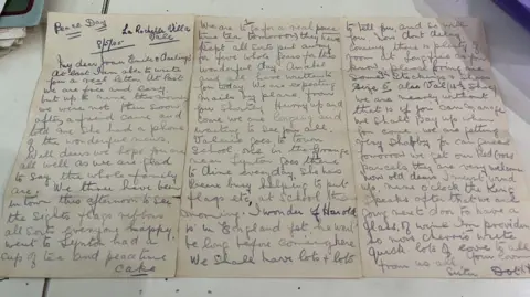 A picture of the letter that is handwritten. It is a dark piece of paper with writing written in ink on it. It is date 08/05/1945