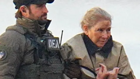 Getty Images A closely-cropped image of Cilia Flores, escorted by a DEA official, appears to show bruising to her face 