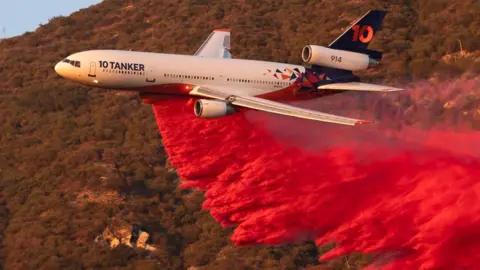 A plane drops bright red fire retardant during the Eaton Fire near Altadena, California, US, on Monday 13 January, 2025