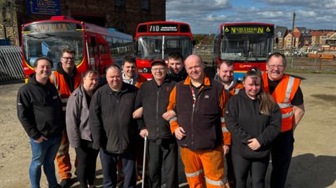 Team members standing in front of buses