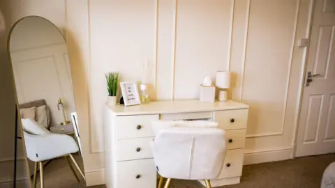 Acquiesce Ltd handout A modern white desk and chair and mirror in an apartment where people having treatment for substance misuse stay. 