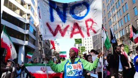 A demonstrator carries a "No War" sign during a protest against war in Iran near the White House.