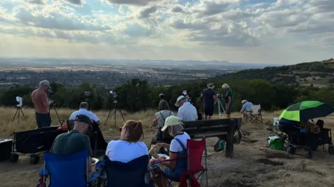 People are sat on chairs while on a large hill