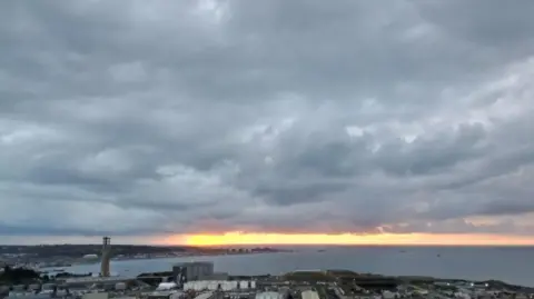 BBC A wide shot of part of Jersey, with the sunsetting over the island.