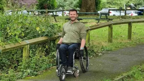 Gary Dawson Man in green space outside in a wheelchair - Gary.