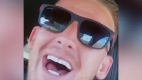 Man with sunglasses smiles into the camera.