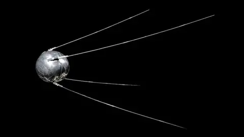 Universal History Archive/Universal Images Group via Getty Images Sputnik 1, a polished metal sphere with four external radio antennas, against a black background 