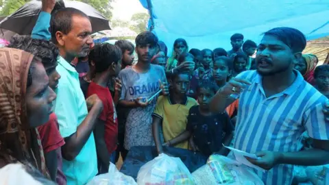 EPA Flood-affected people gather to receive food supplies at a relief center during flooding in a low-lying area in Guwahati, Assam, India, 5 July 2024. 