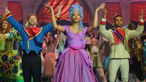Kiefer Sutherland, Savannah Lee Smith, Lucien Laviscount and other cast members in their panto costumes on stage with their arms raised